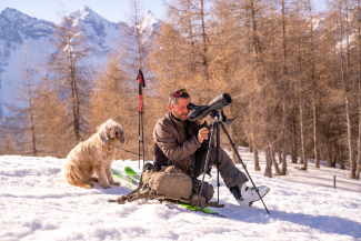 Curdin stellt er sein Spektiv auf und sucht die Hänge nach Wildtieren ab.